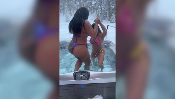 Playboy model and pal don skimpy bikinis to relax in hot tub during snowy weather